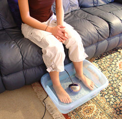 How The QEnergySpa Works - Gal on couch with Feet in foot tub and orb